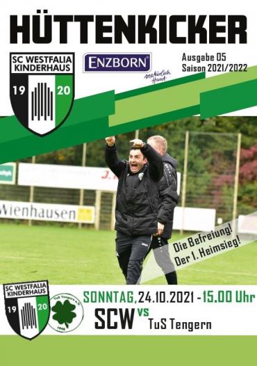 Zwei Männer feiern ein sportliches Ereignis auf einem Fußballfeld mit Publikum im Hintergrund.