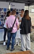 Eine Gruppe von Menschen steht vor einem Messe- oder Ausstellungsstand mit dem Logo UKM.