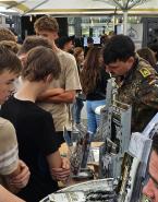 Eine belebte Messehalle mit vielen Menschen an einem Ausstellungsstand.