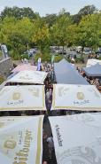 Ein großes Outdoor-Event mit vielen Markständen und Zelten verschiedener Bierbrauereien in einer parkähnlichen Umgebung.
