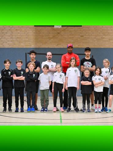 Eine Gruppe junger Männer eines Sportteams posiert in einer Sporthalle.