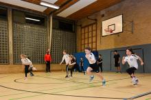 Mehrere Schüler spielen in einer großen, gut ausgestatteten Sporthalle.