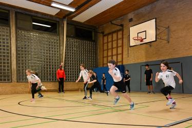 Mehrere Schüler spielen in einer großen, gut ausgestatteten Sporthalle.