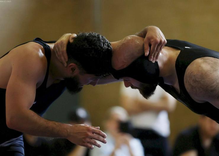 Zwei Männer bei einem Nahkampf-Training, die sich in einer intensiven Griff-Position gegenüberstehen.