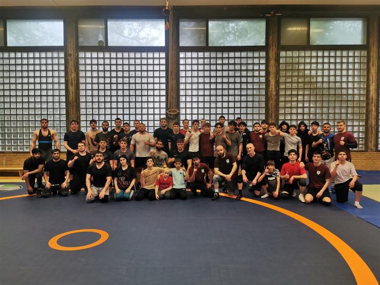 Eine große Gruppe von Menschen posiert zusammen in einer Sporthalle.