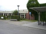 Ein modernes Bürogebäude mit einem überdachten Parkbereich und einem Parkschild.