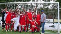 Eine große Gruppe von Fußballspielern posieren vor einem Fußballtor auf einem Sportplatz.