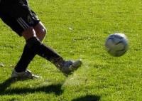 Ein Fußballspieler tritt einen Ball auf einem grünen Rasenfeld.
