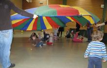 Großes, buntes Spielzelt in einer Sporthalle mit vielen Kindern, die spielen.