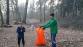 Ein Mann und ein Junge in einem nebligen Wald, die einen großen orangefarbenen Müllsack halten.