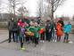 Eine große Gruppe von Menschen, darunter viele Kinder, steht im Freien und trägt Blumen.