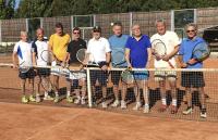 Eine Gruppe von Männern in sportlicher Kleidung steht auf einem Tennisplatz und hält Tennisschläger.