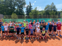 Eine große Gruppe von Kindern und Jugendlichen posieren gemeinsam auf einem roten Sportplatz.