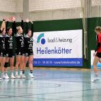 Ein Sportteam posiert auf einem Sporthallenboden vor Werbebanden mit Sponsorlogos.