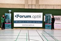 Großformatiges Werbebanner mit dem Schriftzug Forum.optik in einem Sporthallenambiente.