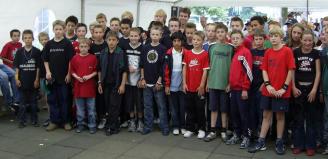 Großes Gruppenfoto von vielen Männern, die draußen vor einem Gebäude zusammenstehen.