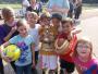 Eine Gruppe von Kindern posiert im Freien mit mehreren Sportbällen.