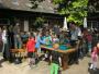Eine Gruppe von Menschen, bestehend aus Kindern und Erwachsenen, spielt an einem Pooltisch im Freien.