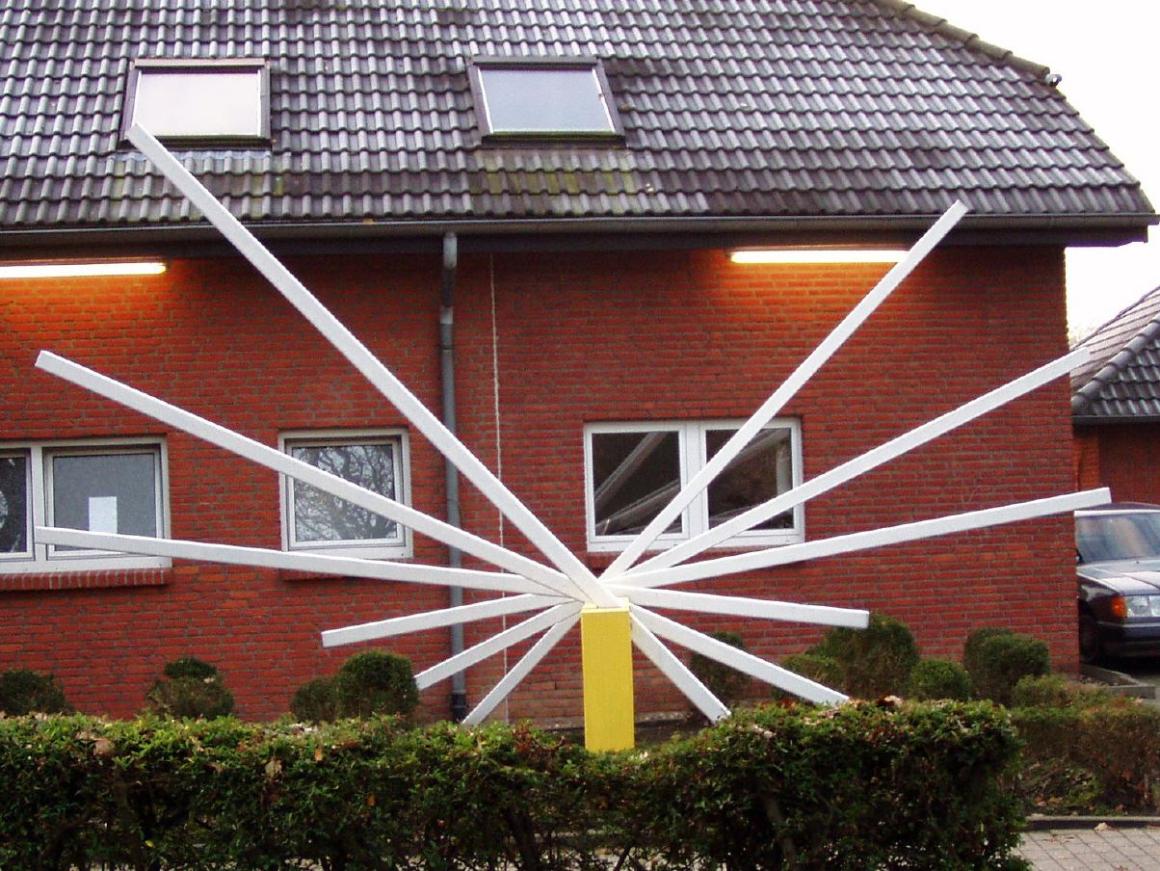 Ein modernes Backsteinhaus mit einem auffälligen, weißen, strahlenförmigen Kunstobjekt an der Fassade.