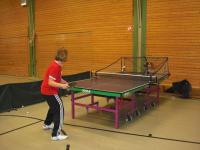 Ein Mann steht bei einem aufgebauten Tischtennis-Tisch in einer Sporthalle.
