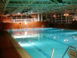 Innenaufnahme eines großen, beleuchteten Schwimmbeckens mit industrieller Hallenarchitektur.