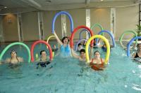Mehrere Personen spielen in einem Schwimmbecken mit bunter Schwimmhilfen und Rahmen.