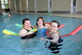 Vier Frauen posieren fröhlich zusammen in einem Schwimmbecken.