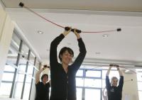Eine Gruppe von Menschen macht ein Fitness-Training mit Widerstandsbändern in einem hellen Studio.