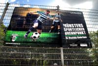 Großes Werbeplakat für einen Sportverein mit zwei Fußballspielern und dem Titel Münsters Sportlicher Brennpunkt.