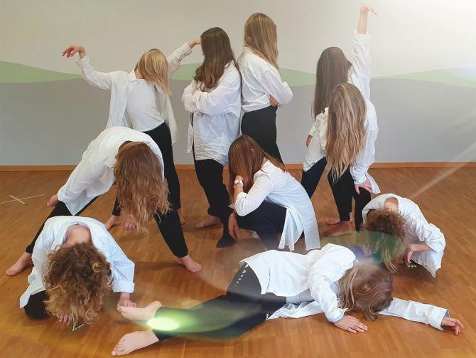 Gruppe von Frauen, die gemeinsam Yoga- oder Dehnübungen in einem Studio durchführen.
