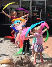 Eine Gruppe junger Mädchen tanzt im Freien und schwingt bunte, fließende Schleifen.
