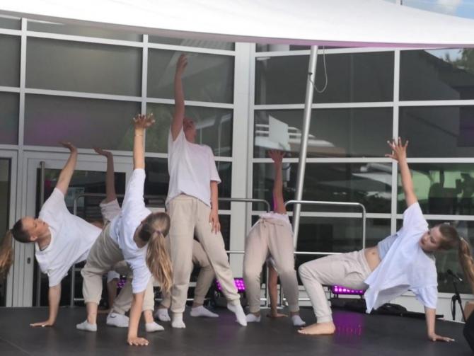 Eine Gruppe von Menschen führt eine Yoga- oder Fitnessübung in einer großen Halle durch.