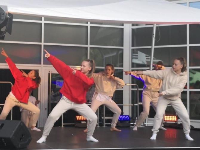 Eine Gruppe von Jugendlichen führt einen choreografierten Tanzauftritt auf einer Bühne durch.