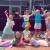 Eine Gruppe von Kindern in bunten Kostümen posieren und lächeln während einer Gruppenaufführung.
