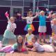 Eine Gruppe von Kindern in bunten Kostümen posieren und lächeln während einer Gruppenaufführung.