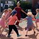 Eine Gruppe von Erwachsenen und Kindern spielt draußen auf einem gepflasterten Platz.