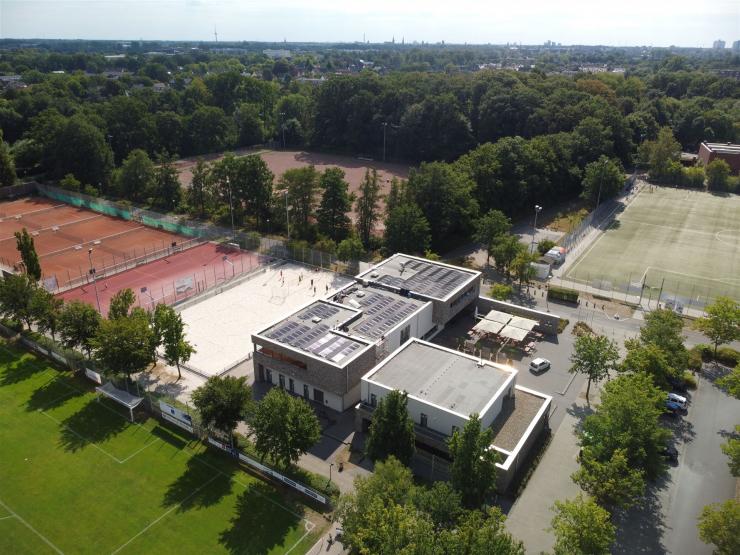 Luftaufnahme eines großen Sportkomplexes mit mehreren Sportplätzen und Gebäudekomplexen, umgeben von viel Grün.